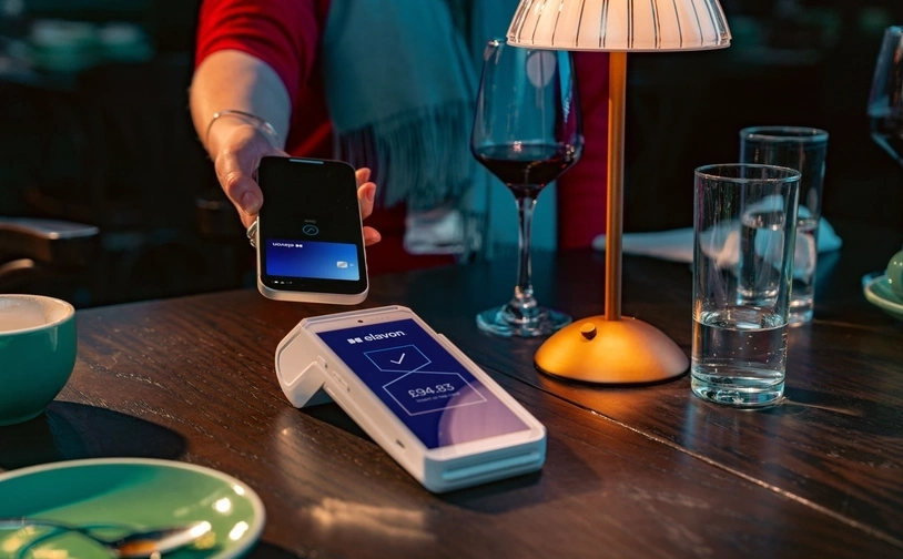 Contactless card payment at a café table using a handheld card reader during a casual dining experience