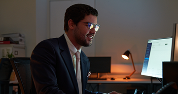 Person working remotely on a laptop while relaxing on a hotel bed in a modern hotel room