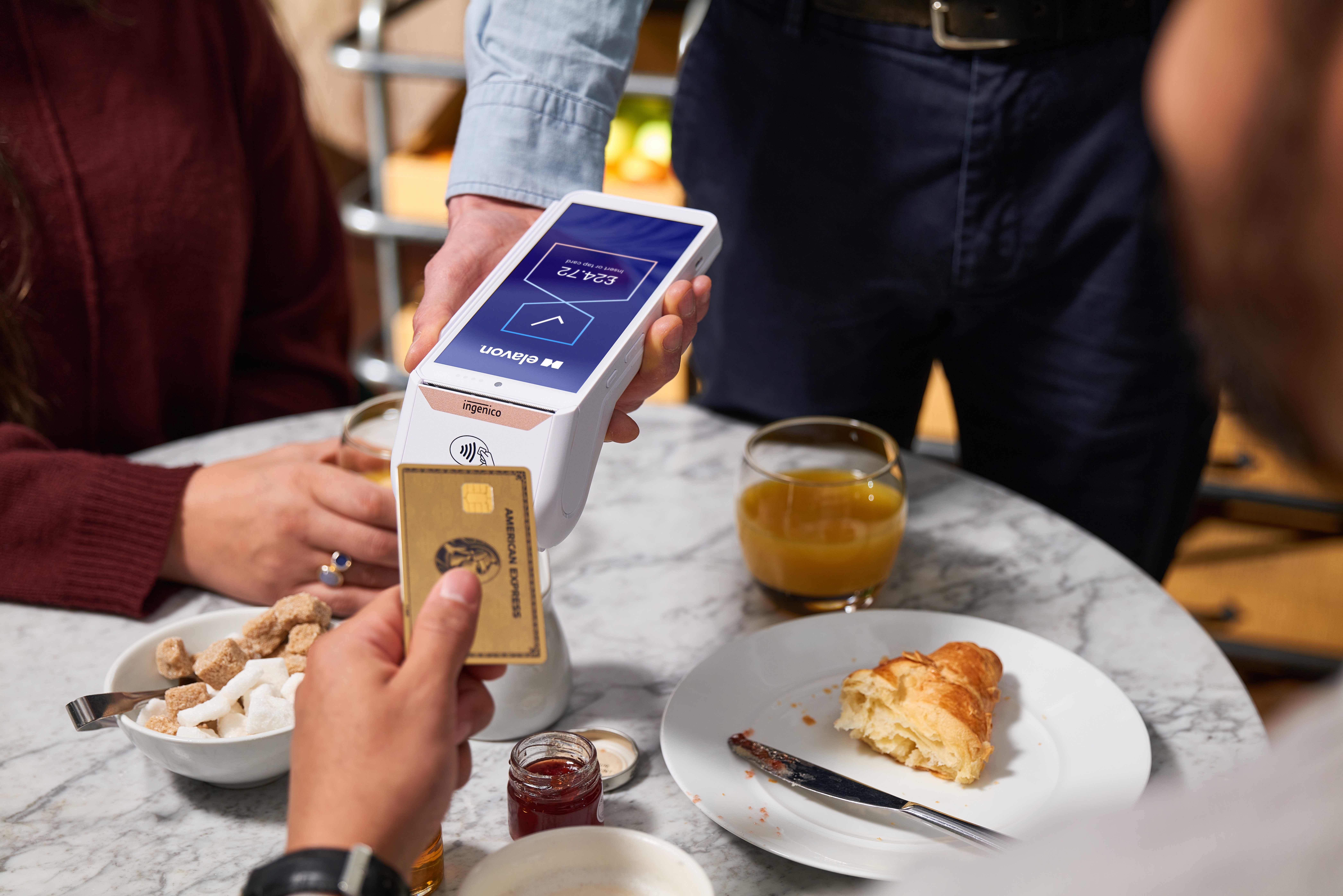 Contactless card payment at a bar using a handheld POS terminal while bartender serves cocktails